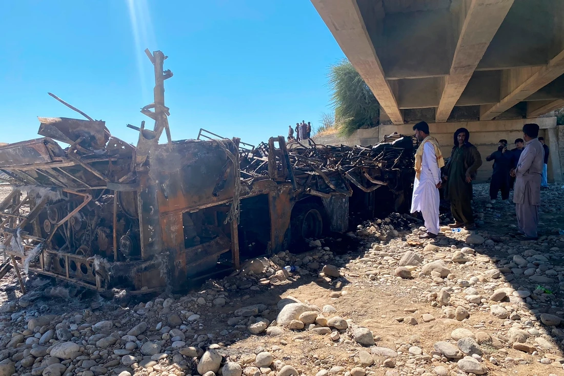 People look at the burnt wreckage of a bus after an accident in Bela, Lasbela, Balochistan, Pakistan, Sunday, Jan. 29, 2023. (AP Photo)