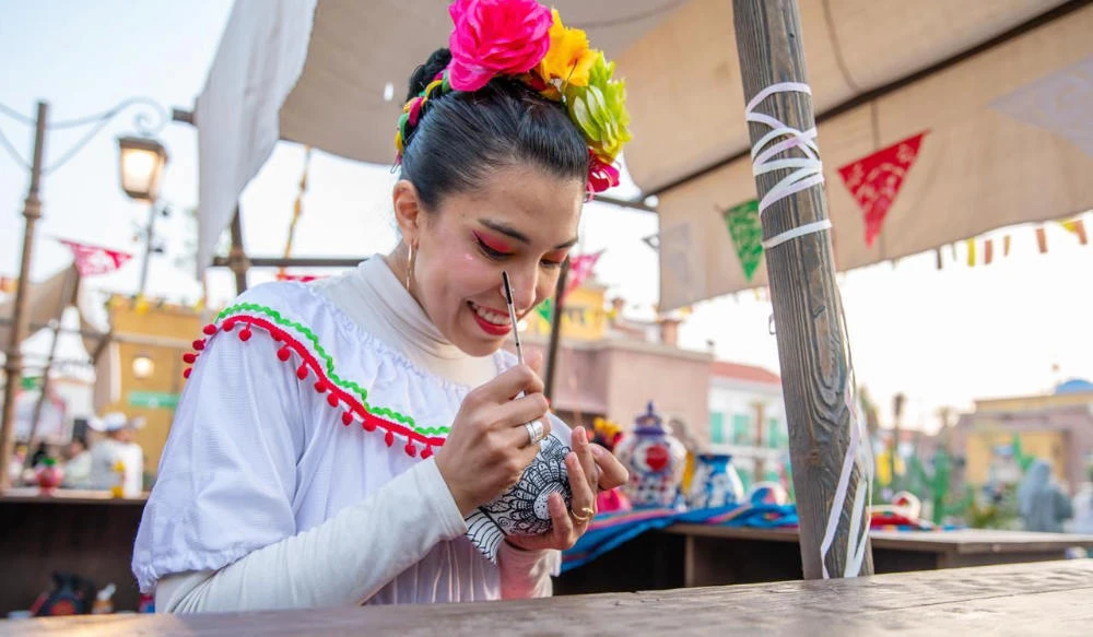 A Mexican woman can be viewed skillfully applying distinctive art to pottery to highlight their country’s rich artistic identity. (Supplied)