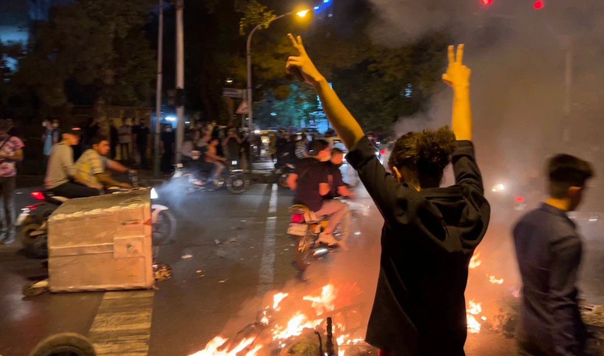 A demonstrator raising his arms and makes the victory sign during a protest for Mahsa Amini in Tehran on September 19, 2022. (AFP)