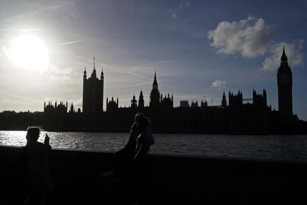 People pose for a photograph on the banks of the River Thames with The Palace of Westminster and Elizabeth Tower (more commonly known by the name of the bell in the clocktower, 'Big Ben') seen behind, in London on October 26, 2022. (AFP)