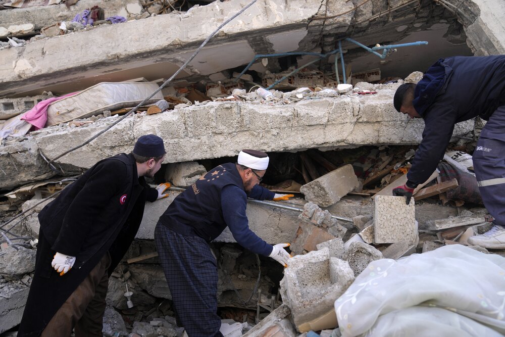 People and emergency teams search for survivors in the rubble of a destroyed building, in Iskenderun town, southern Turkiye, on Feb. 7, 2023. (AP)