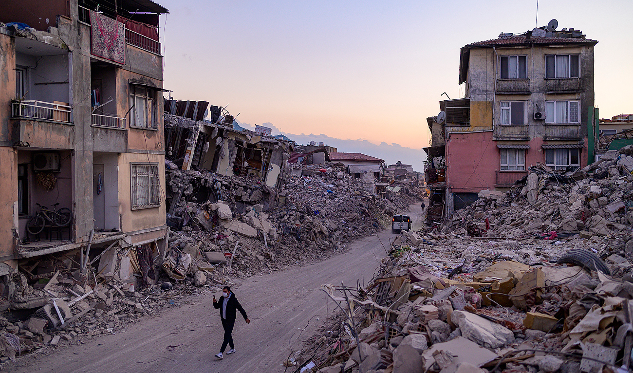 A man walks past collapsed buildings in Antakya, southern Turkey on February 20, 2023. (Photo courtesy: AFP)