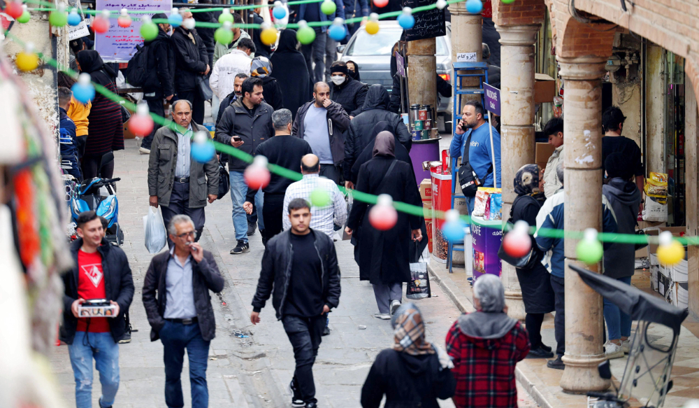 Iranians gather in a commercial area in Tehran. Iran’s currency continued its slide to hit new lows, weighed by Tehran’s increased isolation. (AFP file photo)