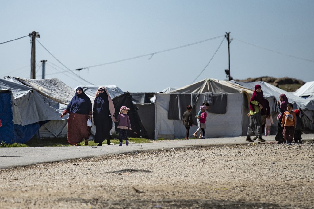 Women with children walk at Camp Roj, where relatives of people suspected of belonging to the Daesh group are held, in the countryside near al-Malikiyah (Derik) in Syria's northeastern Hasakah province (AP)