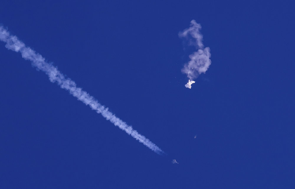 A fighter jet flies past the remnants of a large balloon after it was shot down above the Atlantic Ocean. (AFP)