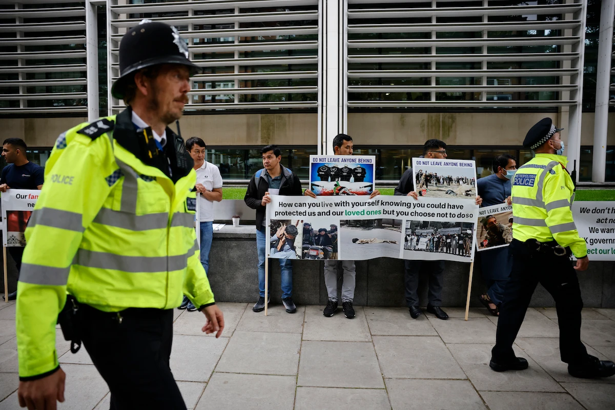 Police officers walk by as former interpreters for the British forces in Afghanistan demonstrate outside the Home Office in central London. (File/AFP)