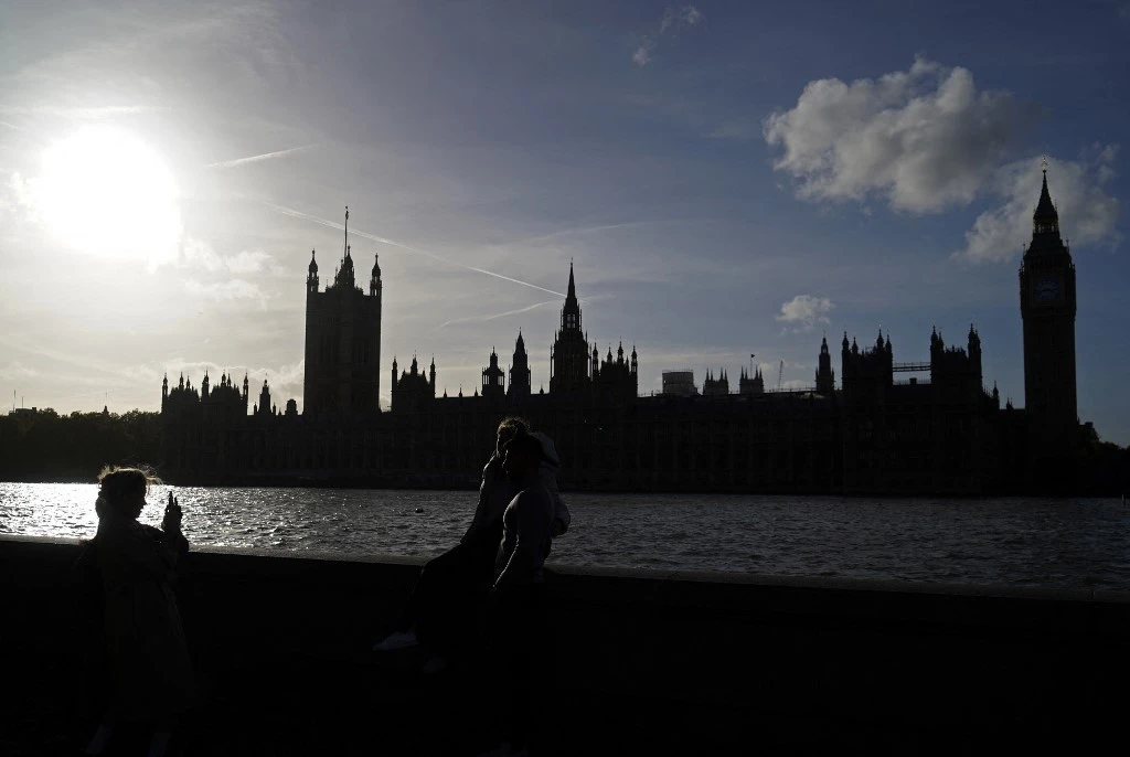 People pose for a photograph on the banks of the River Thames with The Palace of Westminster and Elizabeth Tower (more commonly known by the name of the bell in the clocktower, 'Big Ben') seen behind, in London on October 26, 2022. (AFP)