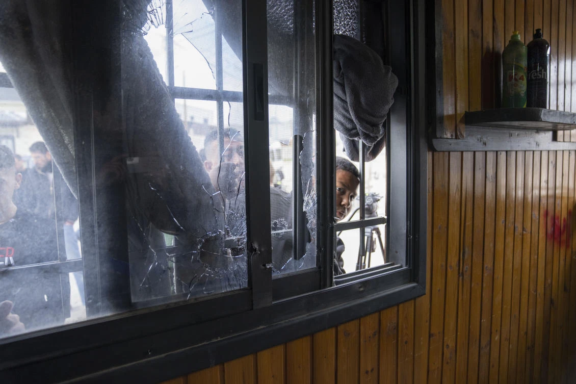 A Palestinian youth inspects damaged and blood stained furniture from a shattered window at the site of an Israeli army raid in the West Bank's Aqabat Jabr refugee camp, in Jericho, Monday, Feb. 6, 2023. (AP)
