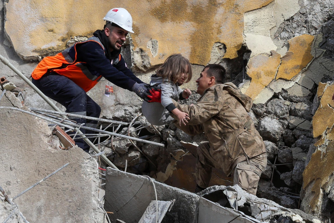 Muhammet Ruzgar, 5, is carried out by rescuers from the site of a damaged building, following an earthquake in Hatay (REUTERS)