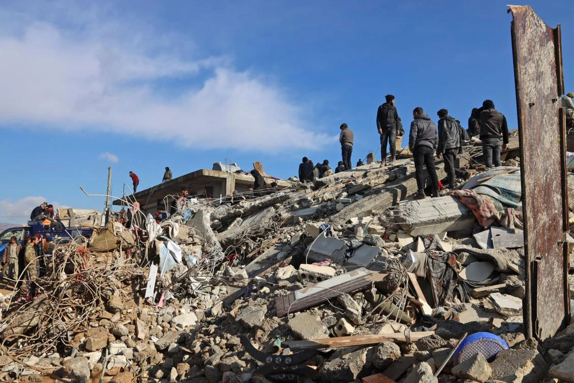 Syrian rescuers gather above the rubble of a collapsed building, in the town of Jandaris, in the rebel-held part of Aleppo province, as a search operation continues following a deadly earthquake. (AFP)