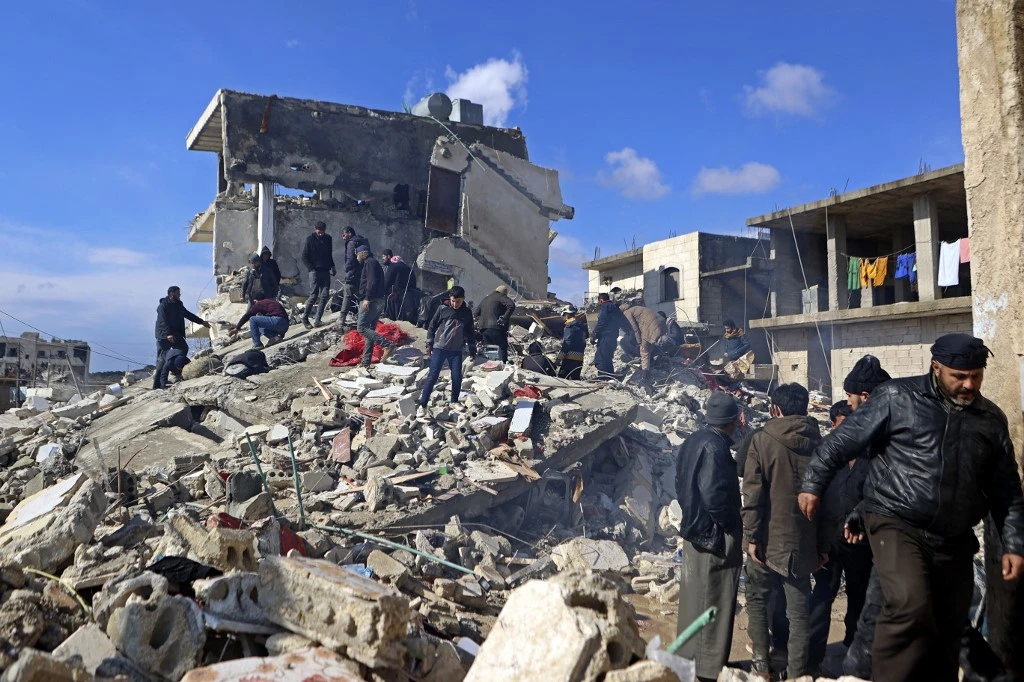 Syrians search for victims and survivors under the rubble of a collapsed building in the rebel-held town of Jindayris (AFP)