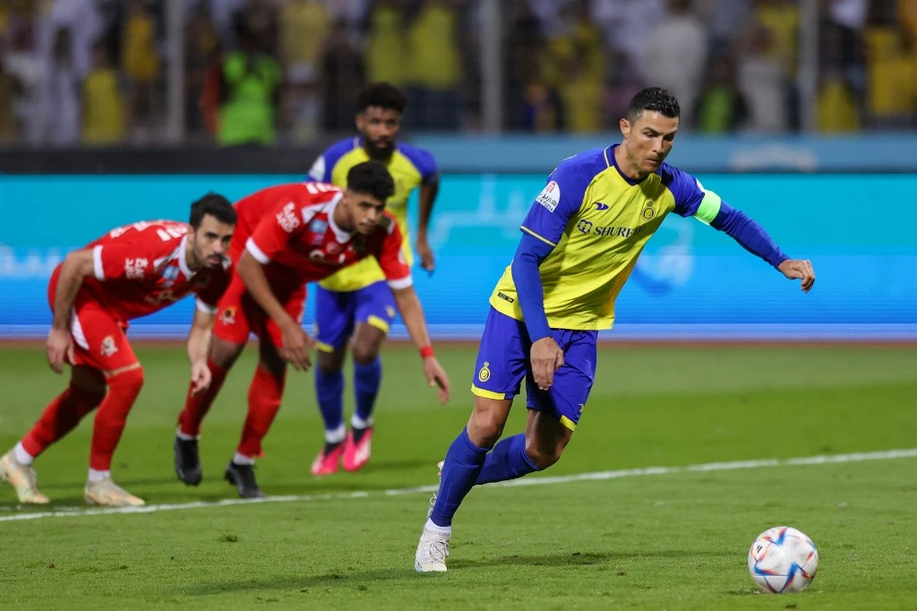 Nassr's Portuguese forward Cristiano Ronaldo (R) shoots to score his team's third goal from a penalty during the Saudi Pro League football match between Al-Wehda and Al-Nassr at the King Abdulaziz Stadium in Mecca (AFP)