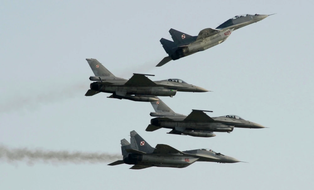 Two Polish Air Force Russian made Mig 29's fly above and below two Polish Air Force US made F-16's fighter jets during the Air Show in Radom, Poland, Aug. 27, 2011. (AP)