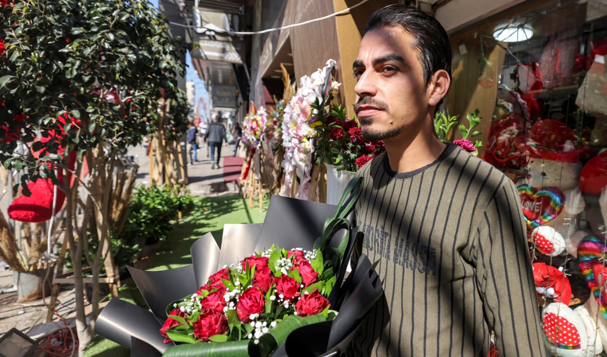 A man stands with a bouquet of flowers outside a florists' shop in Gaza City on Valentine's Day on February 14, 2023. (AFP)