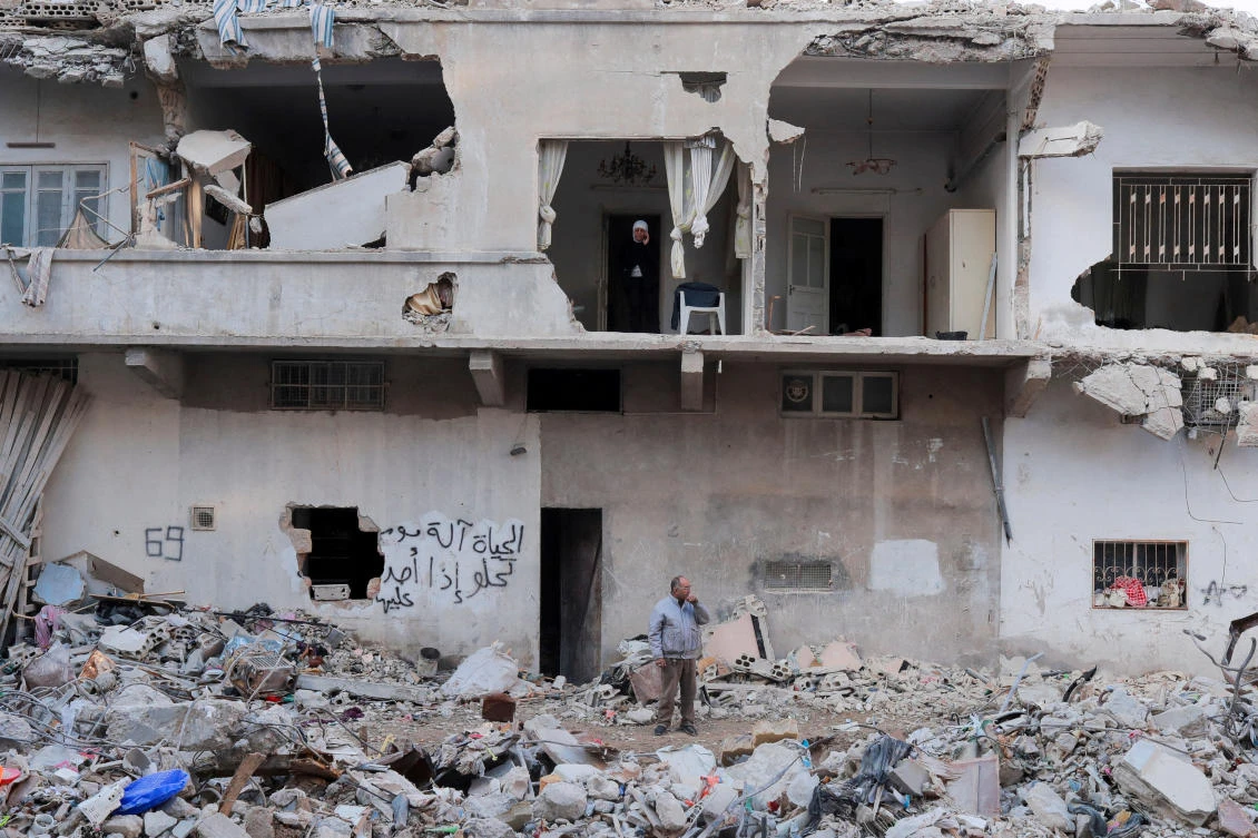 People stand in their collapsed home that was damaged in a deadly earthquake in Jableh, Syria, February 15, 2023. (Reuters)