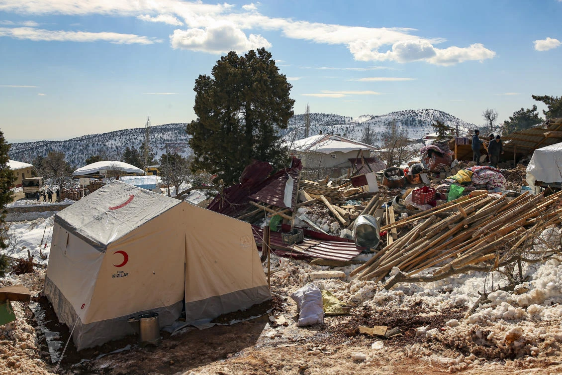 People walk by collapsed houses in Buyuknacar village in Kahramanmaras, Turkey, Wednesday, Feb. 15, 2023. (AP)