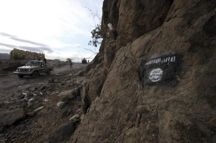 Houthi militia drive a truck past an Al-Qaeda flag, painted on the side of a hill, along a road in Almnash, Rada’a District, Al Bayda Governorate, Yemen, Nov. 22, 2014. (Reuters)