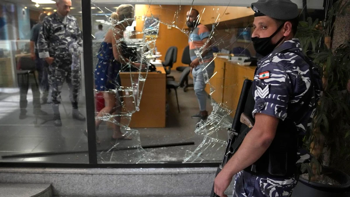 A policeman stands guard next to a bank window that was broken by depositors, Beirut, Lebanon, Sept. 14, 2022. (AP Photo)