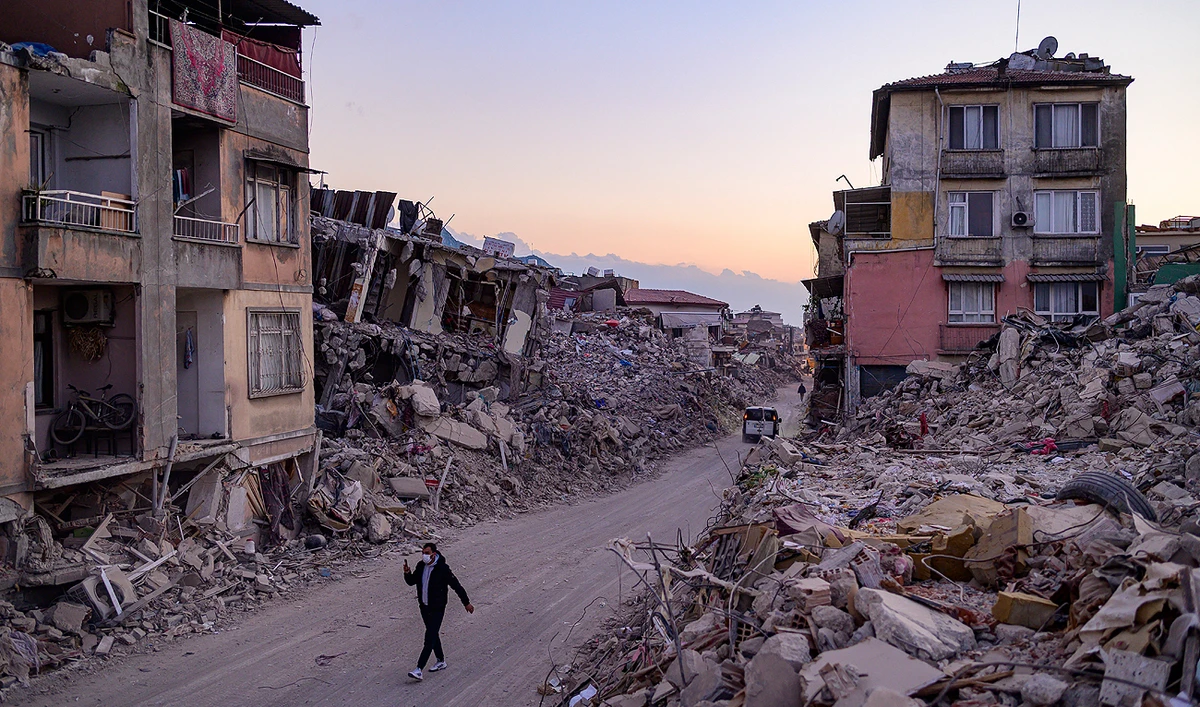 A man walks past collapsed buildings in Antakya, southern Turkey on February 20, 2023. (Photo courtesy: AFP)