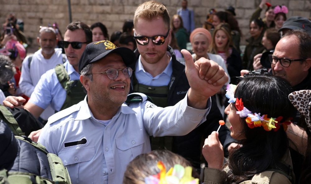 Itamar Ben-Gvir greets Israeli settlers dressed in Purim costumes, Hebron, occupied West Bank, Mar. 7, 2023. (AFP)