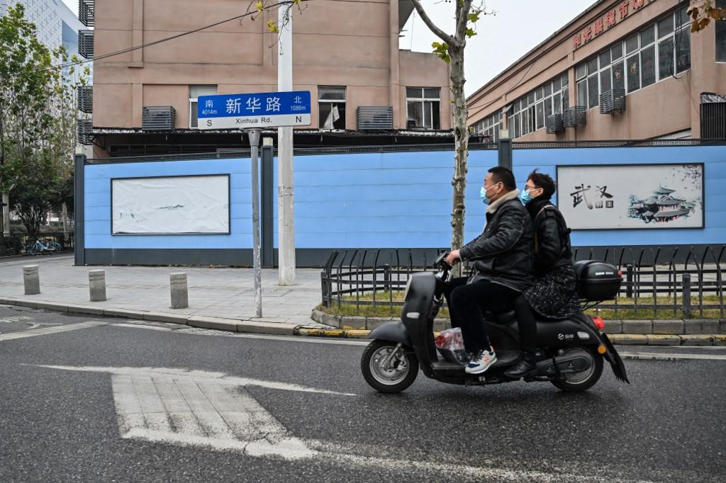 Above, residents on a scooter pass by the closed Huanan Seafood Wholesale Market, where the COVID-19 coronavirus was first detected. (AFP)