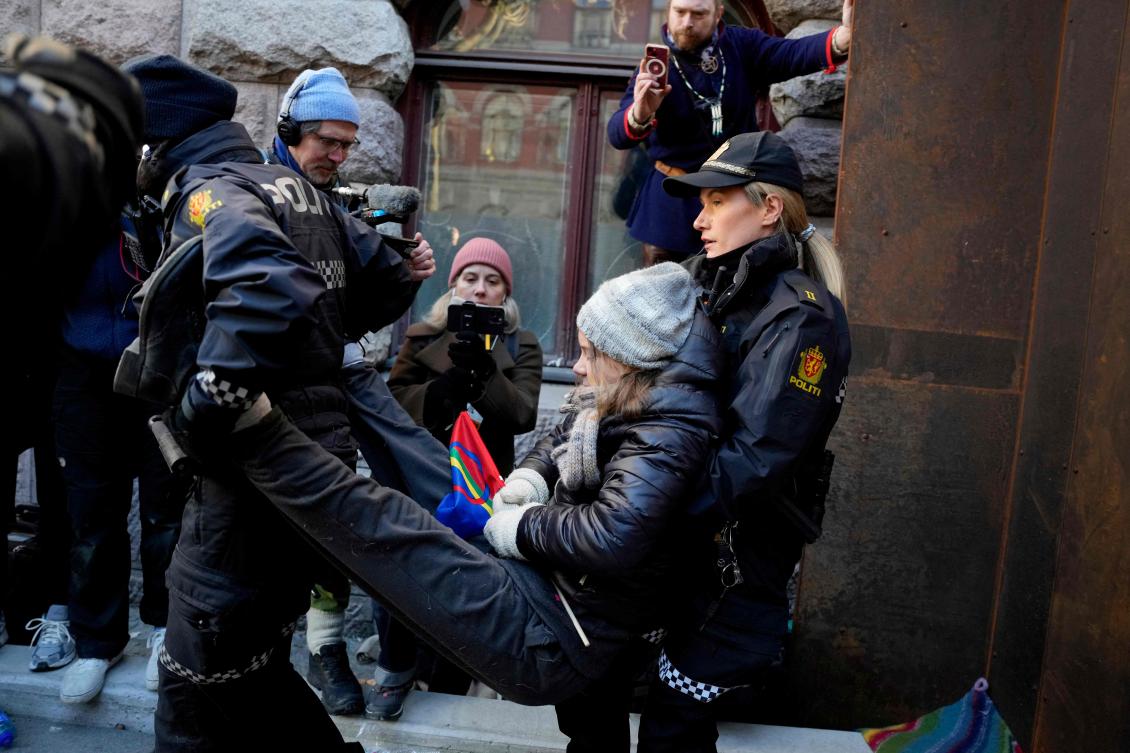 Policewomen carry away Swedish climate activist Greta Thunberg, center, as she and other campaigners to protest against wind turbines built on land traditionally used to herd reindeer in Oslo, Norway on March 1, 2023. (NTB/AFP)