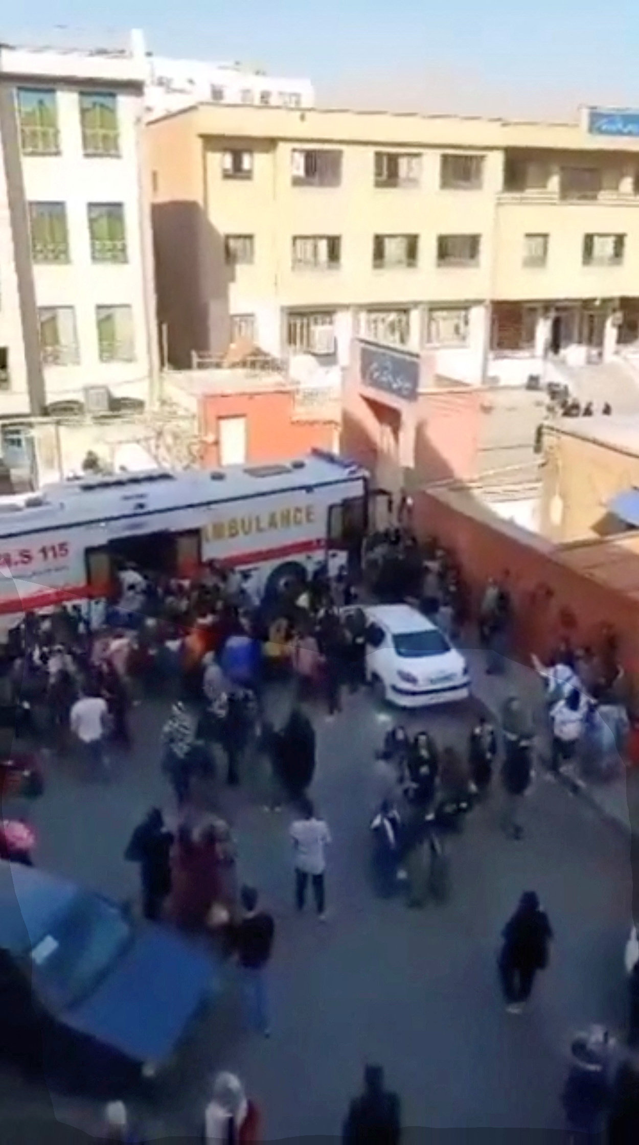 People gather around an ambulance outside a girls school after reports of poisoning in Fardis, Alborz province, Iran in this undated video still image released March 1, 2023. (Reuters)
