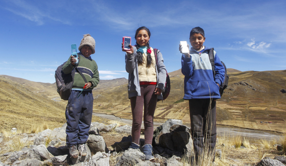 (L-R) Siblings Alvaro, 10, Roxana, 16, and Juan Carlos Cabrera, 13, show their mobile phones as they search for signal on top of a hill in order to attend their virtual classes during the COVID-19 novel coronavirus pandemic, near their house in the remote highland community of Conaviri, district of Manazo, in the Peruvian Andes close to Lake Titicaca and the border with Bolivia, early July 24, 2020. (AFP)