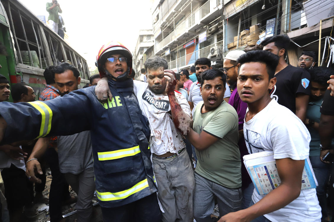 Fire officials and locals carry an injured person to hospital after an explosion in a seven-story commercial building happened in Dhaka killing at least 14 people and injuring dozens, on Mar. 7, 2023. (AP)