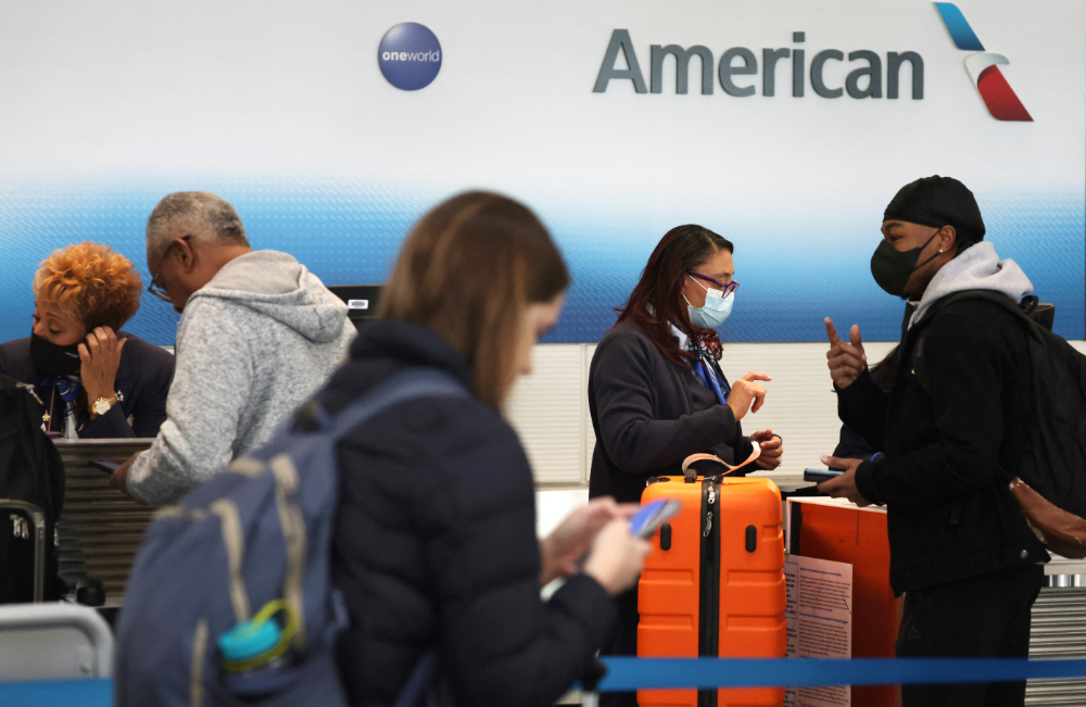 Employees of American Airlines help check in passengers at Ronald Reagan Washington National Airport on January 11, 2023 in Arlington, Virginia. (AFP)