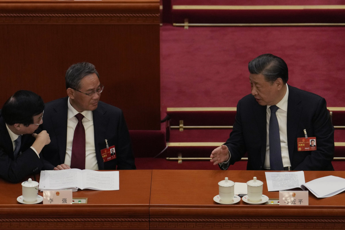 Chinese President Xi Jinping, right, speaks to Politburo Standing Committee members Wang Huning, left, and Li Qiang during a session of China's National People's Congress (NPC) in Beijing on March 7, 2023. (AP Photo/Ng Han Guan)