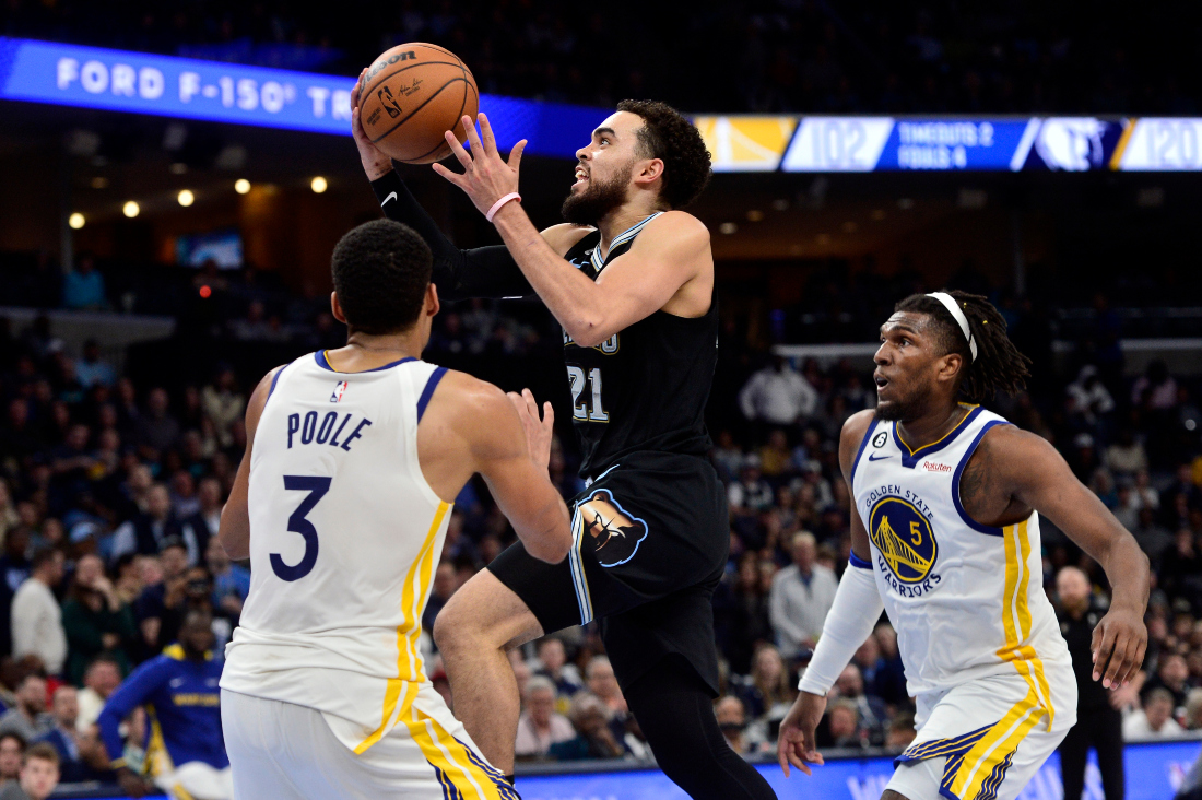 Memphis Grizzlies guard Tyus Jones (21) drives to the basket between Golden State Warriors guard Jordan Poole (3) and forward Kevin Looney in the first half of an NBA game in Memphis, Tenn. (AP)