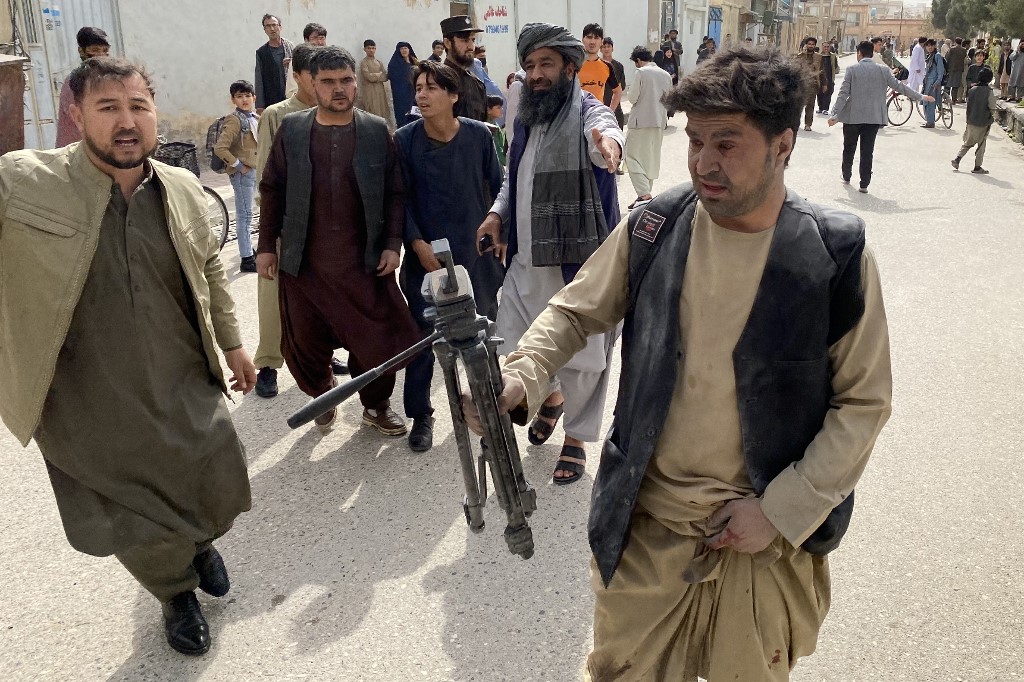 A wounded journalist holds a camera tripod back near the site of a bomb blast during an event commemorating the media in Mazar-e-Sharif, Afghanistan, on March 11, 2023. (AFP)