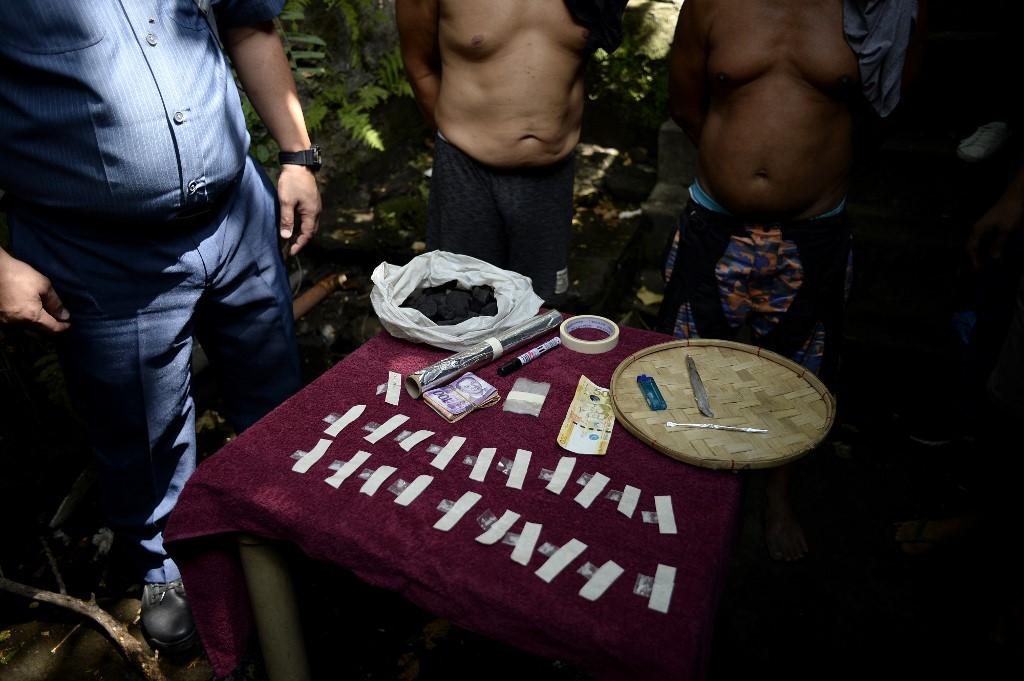 Two suspected drug dealers stand next to drug paraphernalia confiscated from them during a police operation conducted in Manila on March 15, 2018. (AFP file photo)