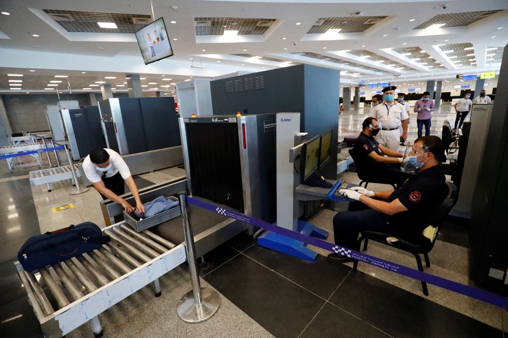 Egyptian policemen, wearing protective face shields, check luggage at the airport (AFP)