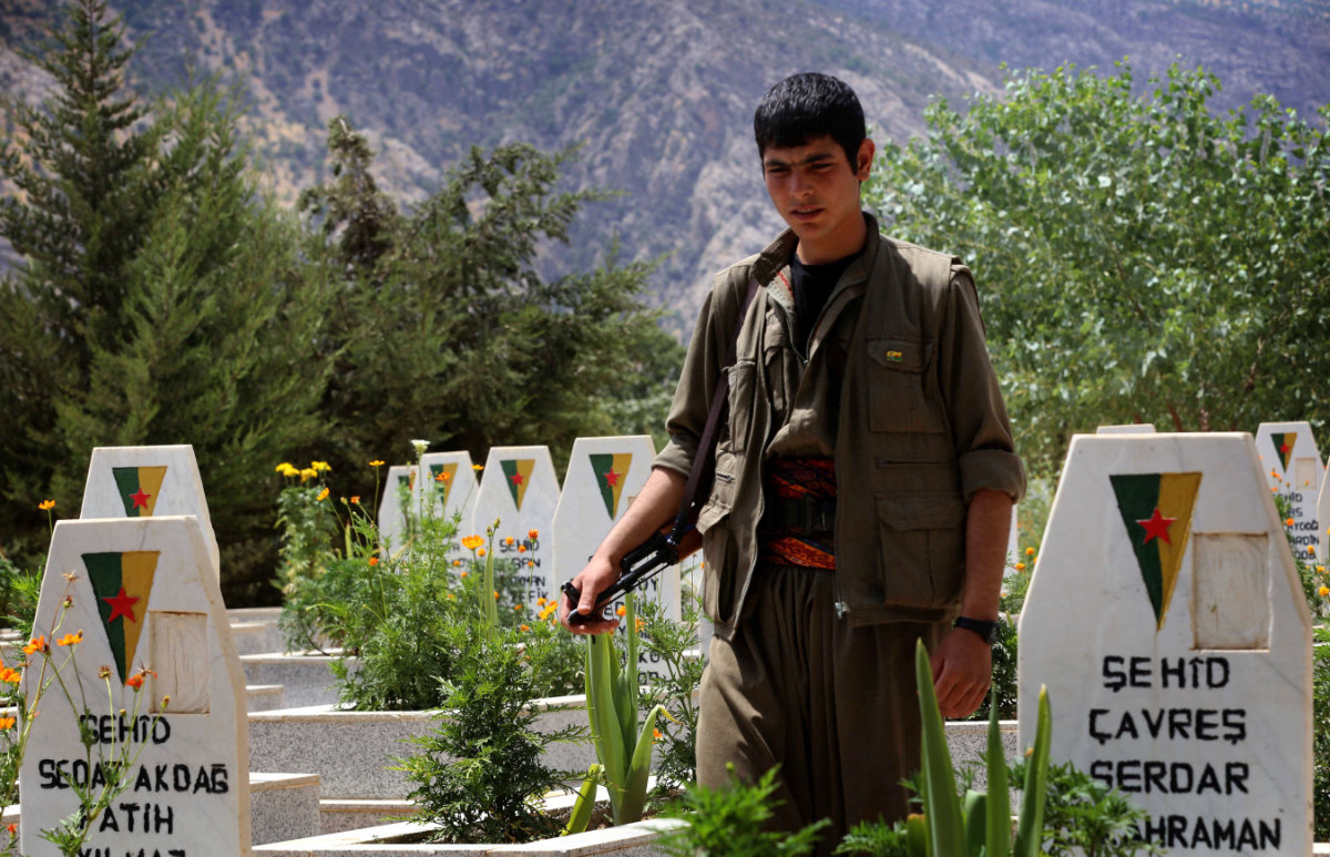 In this picture taken on July 29, 2015, a member of the Kurdistan Workers' Party (PKK) walks past graves at a cemetery deep in the Qandil mountain, the PKK headquarters in northern Iraq. (AFP file)