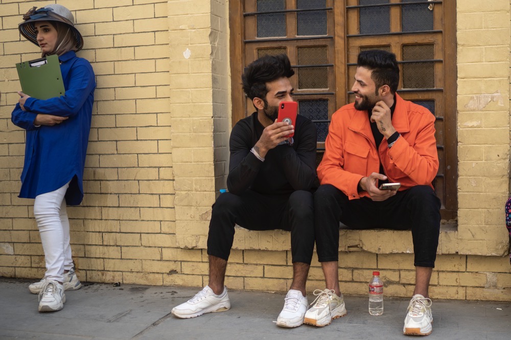 Young men chat near Al-Mutanabbi street in Baghdad, Iraq, Friday, Feb. 24, 2023. Two decades after a U.S.-led invasion, Iraq’s capital today is full of life and a sense of renewal, its residents enjoying a hopeful, peaceful interlude in a painful modern history. (AP Photo/Jerome Delay)