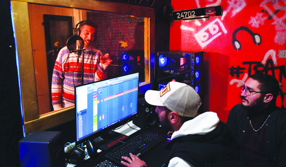 Mohamed Ali Ayari, left, a rapper from a down-at-heel Tunis district, records a song in a booth at a recording studio in Daouar Hicher. (AFP)