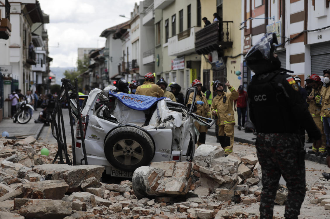 A police officer looks up next to a car crushed by debris after an earthquake shook Cuenca, Ecuador, on Mar. 18, 2023. (AP)