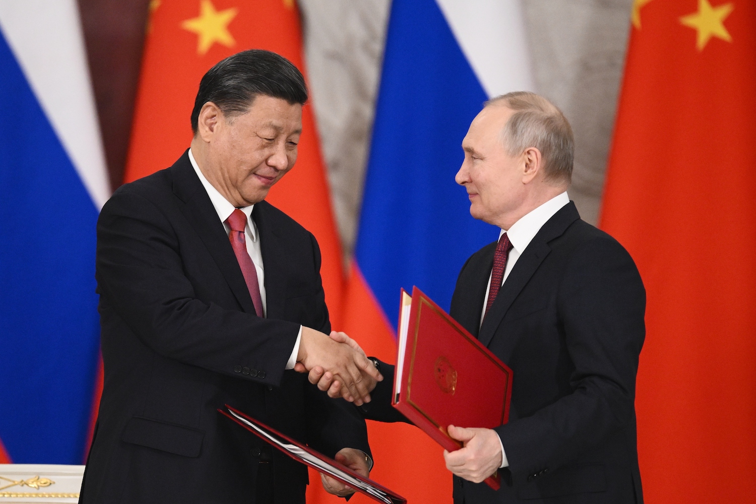 Russian President Vladimir Putin, right, and Chinese President Xi Jinping shake hands as they exchange documents during a signing ceremony in Moscow. (AP)