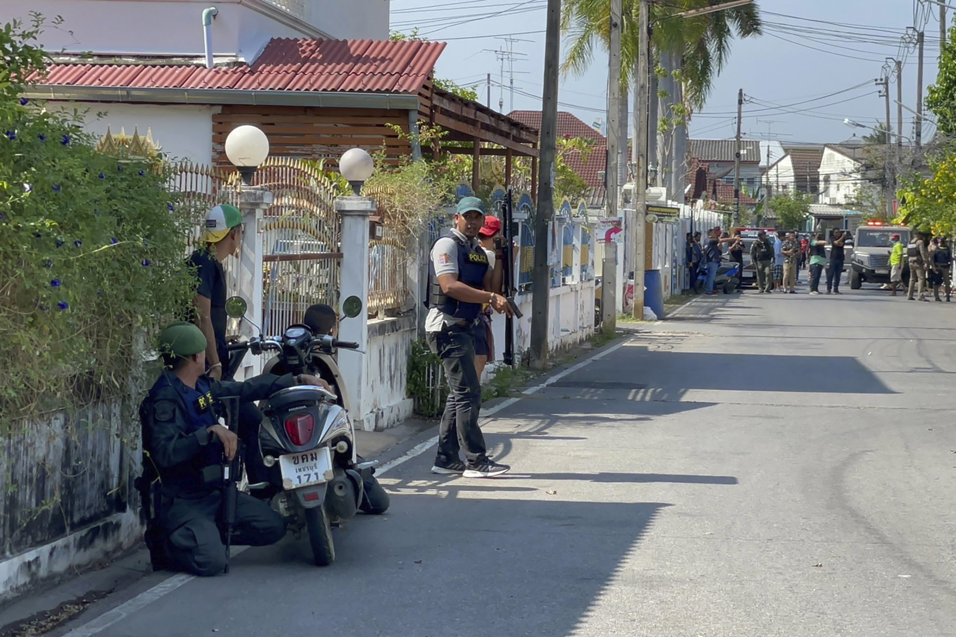 Policemen with guns take positions on a street near the neighborhood of a gunman's house in Phetchaburi province on March 22, 2023. (AP Photo/Supawat Konmun)
