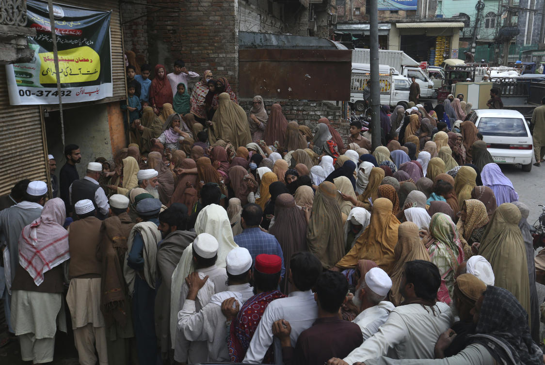 People wait their turn to get a free sack of wheat flour at a distribution point, in Peshawar, Pakistan. (AP)