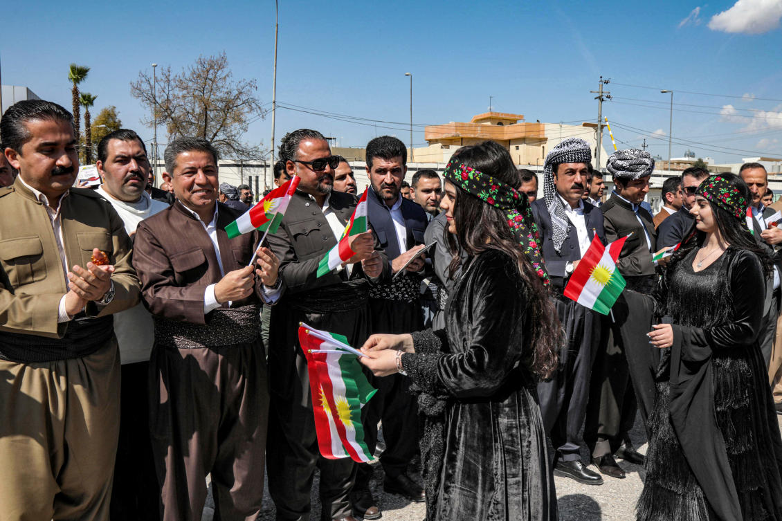 Women hand out small Kurdistan flags to men gathering in the capital of Iraq's northern autonomous Kurdish region Arbil on March 11, 2023. (File/AFP)