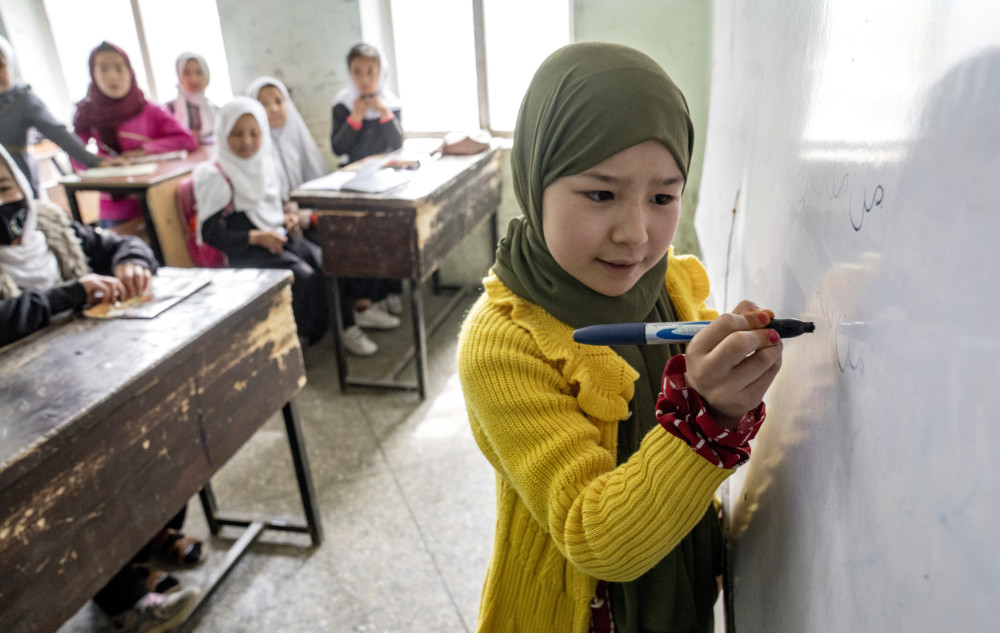 An Afghan school girl writes on a board as girls attend their classroom on the first day of the new school year, in Kabul, Saturday, March 25, 2023. (AP)