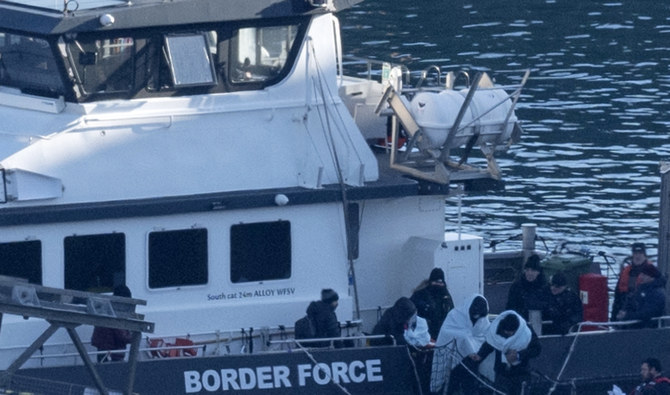 Migrants picked up at sea while attempting to cross the English Channel, are escorted off of the UK Border Force cutter ‘BF Defender’ in Dover, southeast England. (AFP/File)