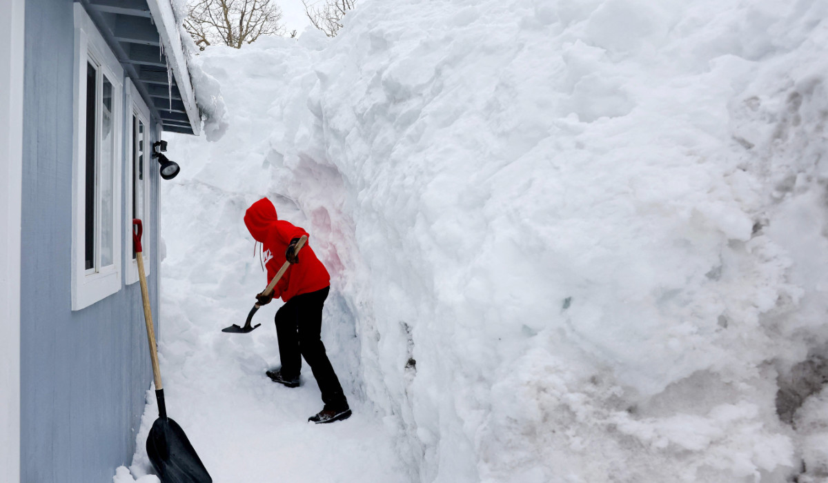Robert Mendoza shovels out his neighbor's home in the Sierra Nevada mountains, still covered in snow from previous storms, as yet another storm system arrives which is predicted to bring heavy snow to higher elevations on March 28, 2023 in Mammoth Lakes, California. (AFP)