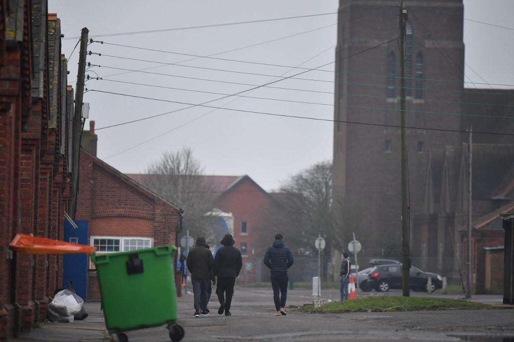 Migrants walk in Napier Barracks, a former military barracks being used to house asylum seekers in Folkestone, southeast England. (File/AFP)