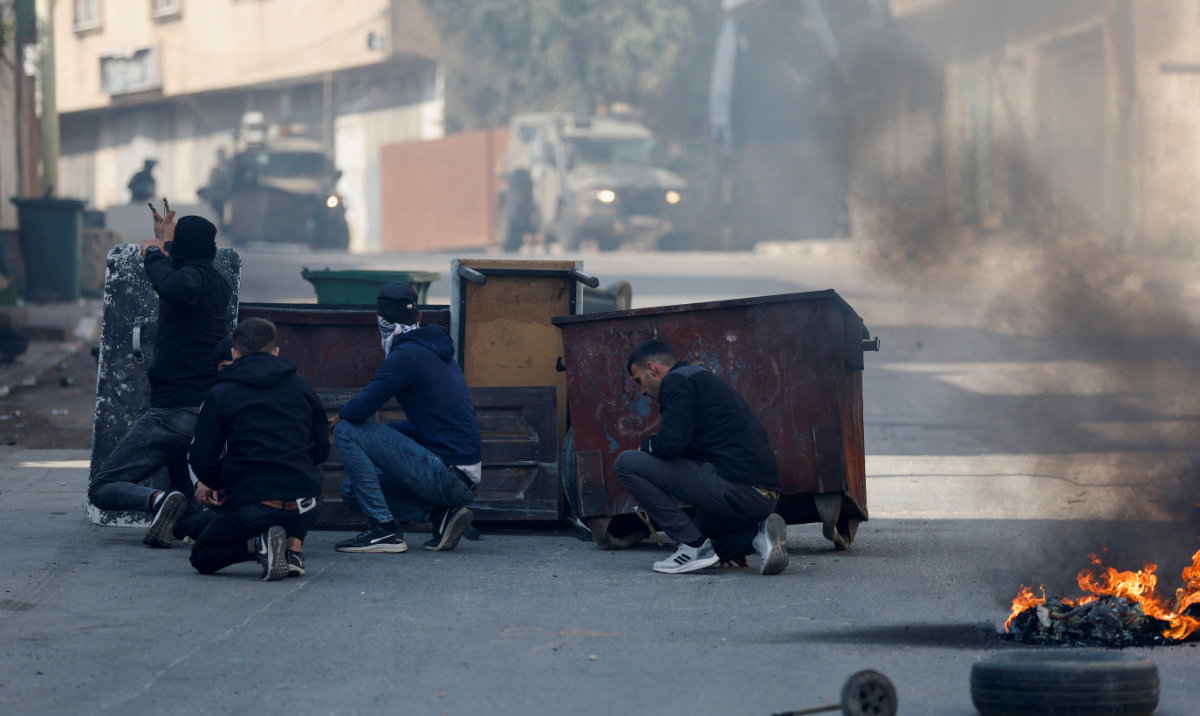 People take cover amid clashes between Palestinians and Israeli forces. (Reuters)