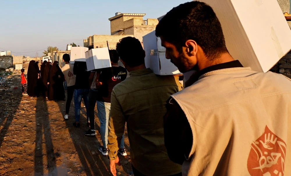 Volunteers from the Trust team distribute food boxes to poor families, near Baghdad, Iraq, Mar. 28, 2023. (Reuters)