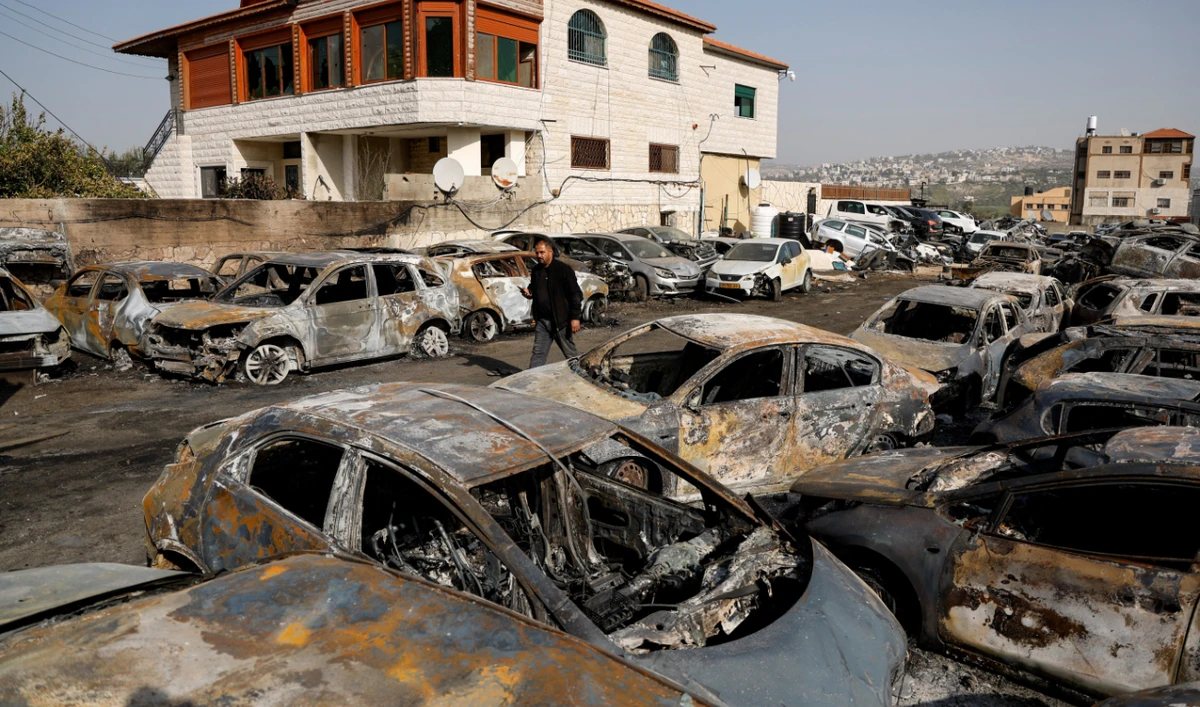 A man walks among cars burnt in an attack by Israeli settlers, following an incident where a Palestinian gunman killed two Israeli settlers, near Hawara in the Israeli-occupied West Bank, February 27, 2023. (Reuters)